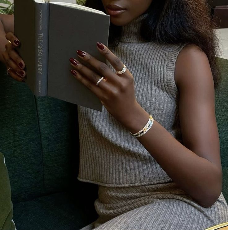 Mulher negra lendo um livro, sentada em ambiente aconchegante, representando introspecção e autoconhecimento feminino.