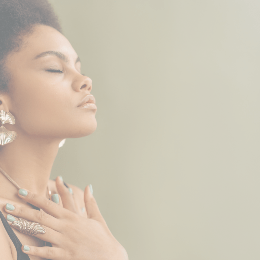 Mulher com expressão serena e mãos sobre o coração, simbolizando o recomeço, o autoconhecimento e a feminilidade autêntica.