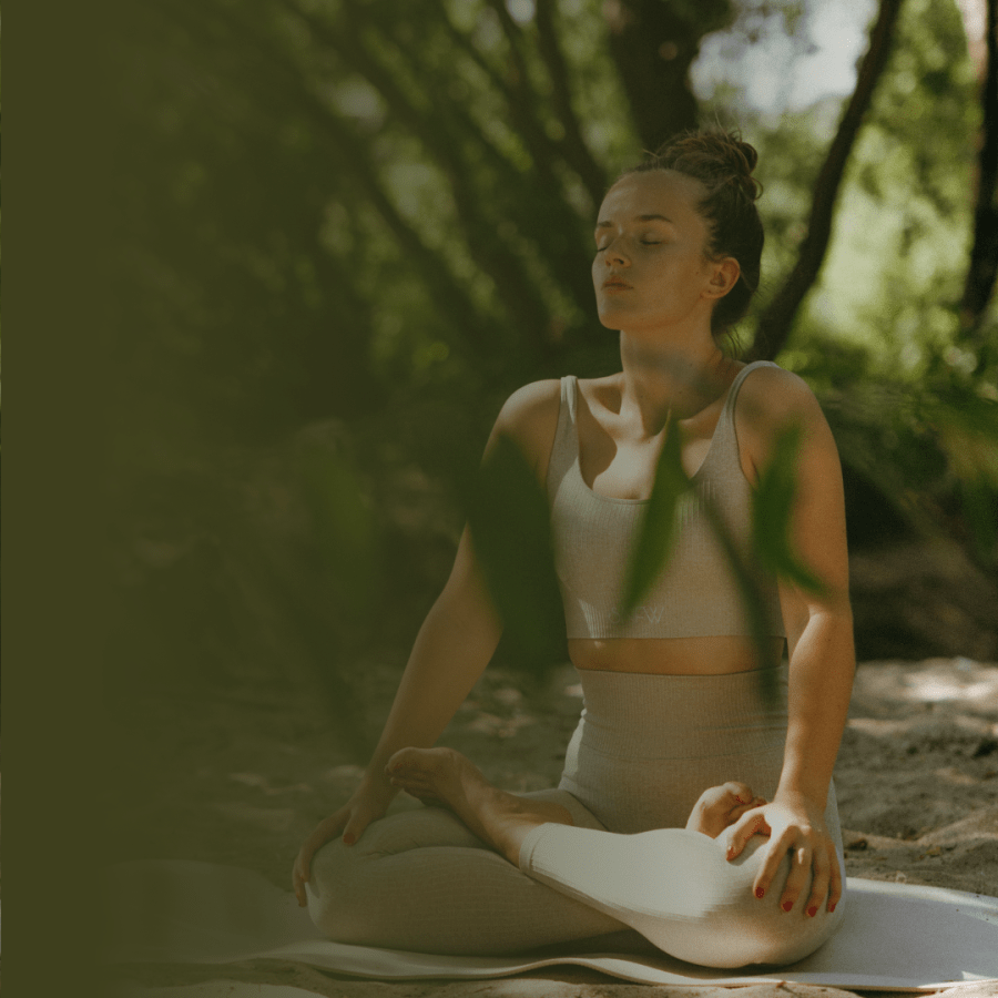 Esta imagem mostra uma mulher sentada em posição de meditação, em um ambiente natural, com luz suave e expressão de serenidade. A foto simboliza autenticidade, conexão interior e a coragem de assumir a própria espiritualidade — temas centrais do texto sobre como esconder quem somos pode travar nossas vendas e nosso propósito.